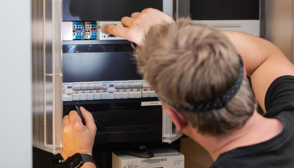 Een technicus inspecteert een elektriciteitskast en bedient de schakelaars.
